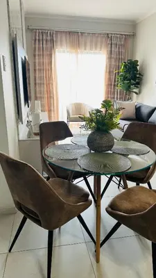 a living room with a table and chairs at Luxury Apartment at 93 on New in Midrand