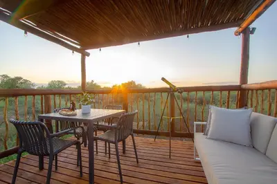 a porch with a table and chairs and a couch at Pillows Luxury Safari Villa, Wood-Fired Hottub, Giraffe-Feeding-Tower, Large Private Pool in Marloth Park
