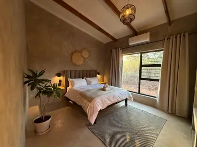 a bedroom with a bed with a potted plant and a window at Pillows Luxury Safari Villa, Wood-Fired Hottub, Giraffe-Feeding-Tower, Large Private Pool in Marloth Park