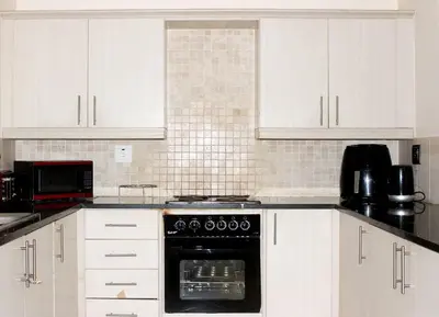 a kitchen with white cabinets and a black oven at cozy 3 bed Duplex ,sleeps 6 with double bathroom in Midrand