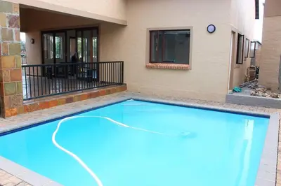 a large blue swimming pool next to a building at cozy 3 bed Duplex ,sleeps 6 with double bathroom in Midrand