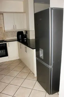 a kitchen with a stainless steel refrigerator and white cabinets at cozy 3 bed Duplex ,sleeps 6 with double bathroom in Midrand