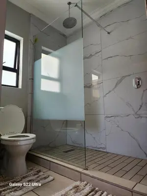 a bathroom with a glass shower with a toilet at Oblique Boutique House in Centurion