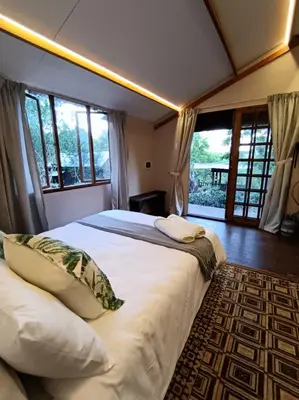 a bedroom with a large white bed with windows at Koinonia Bush Lodge in Hartbeespoort