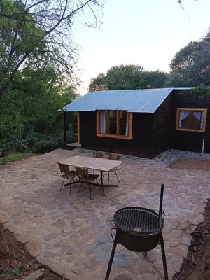 a small cabin with a picnic table and a bench at Koinonia Bush Lodge in Hartbeespoort