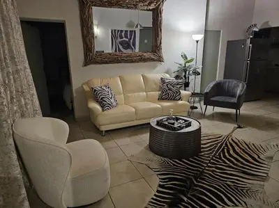 a living room with a couch and chairs and a mirror at Kruger Amani Bush Retreat in Marloth Park