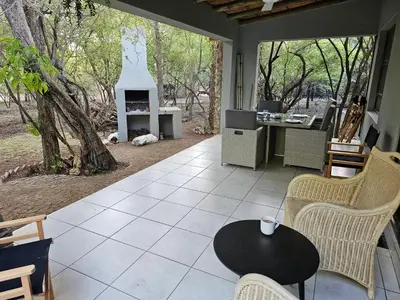 a patio with a table and chairs and a fireplace at Kruger Amani Bush Retreat in Marloth Park