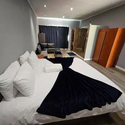a bedroom with a large white bed with black sheets and pillows at Da Vinci Palms in Witbank
