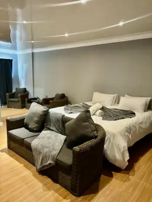 a bedroom with a bed with a chair and a couch at Da Vinci Palms in Witbank