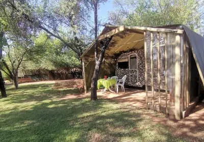 a tent with a table and chairs in a yard at Hartbeespoort Cara-glamping self-cater units in Pretoria