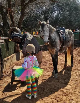 a little girl in a dress standing next to a horse at Hartbeespoort Cara-glamping self-cater units in Pretoria