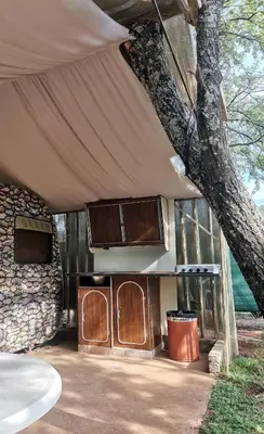 a kitchen under a tent with a tree at Hartbeespoort Cara-glamping self-cater units in Pretoria