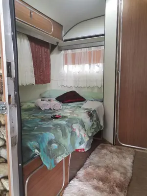 a small bedroom with a bed in a trailer at Hartbeespoort Cara-glamping self-cater units in Pretoria