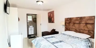 a bedroom with a large bed with a large headboard at Royal Chestnut Guesthouse in Kempton Park
