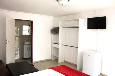 a bedroom with white walls and a tv on the wall at Royal Chestnut Guesthouse in Kempton Park