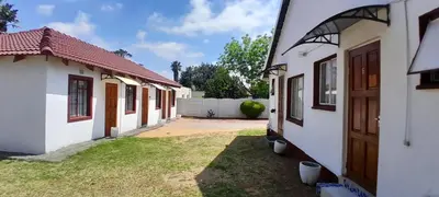 a row of white buildings with a yard at Royal Chestnut Guesthouse in Kempton Park