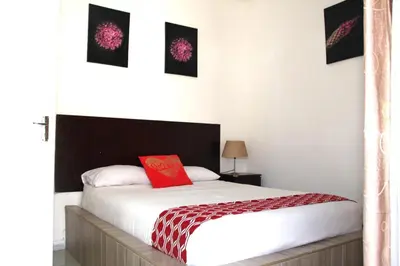 a bedroom with a white bed with a red pillow at Royal Chestnut Guesthouse in Kempton Park