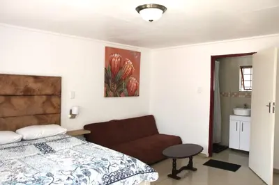a bedroom with a bed and a couch and a painting at Royal Chestnut Guesthouse in Kempton Park