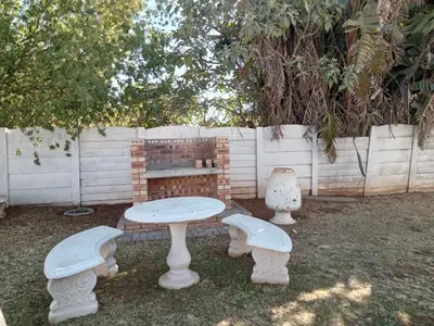 a table and benches in a yard with a fence at Royal Chestnut Guesthouse in Kempton Park