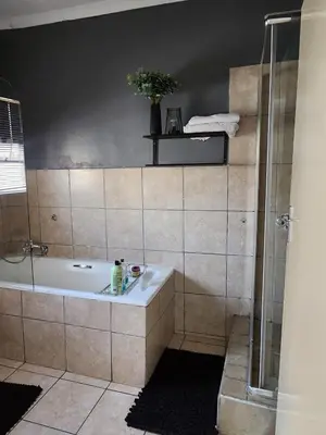 a bathroom with a shower and a bath tub at Pearl palace in Polokwane