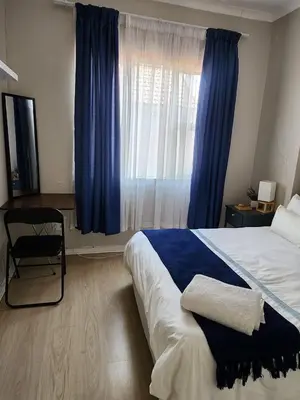 a bedroom with a bed and a window with blue curtains at Pearl palace in Polokwane