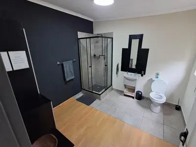 a bathroom with a shower and a toilet and a tv at 26onMagazyn in Polokwane