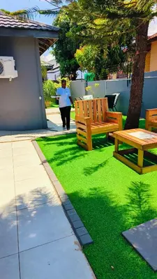 a woman walking down a sidewalk next to two benches at The greenary guest house and restaurant in Thohoyandou