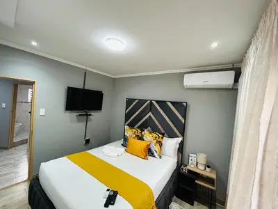 a bedroom with a bed with yellow and orange pillows at The greenary guest house and restaurant in Thohoyandou