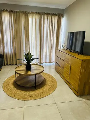 a living room with a coffee table and a flat screen tv at Homely Stay in Kempton Park