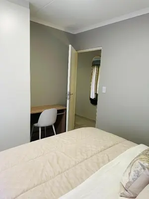 a bedroom with a bed and a desk and a chair at Homely Stay in Kempton Park