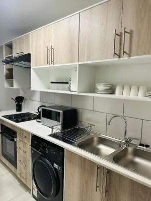 a kitchen with a sink and a stove and a dishwasher at Homely Stay in Kempton Park