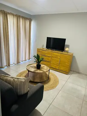 a living room with a tv and a couch and a table at Homely Stay in Kempton Park