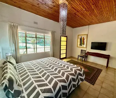 a bedroom with a large bed with a wooden ceiling at The Seed Pod Guesthouse in Haningfontein