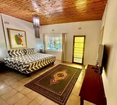 a bedroom with a bed and a table and a window at The Seed Pod Guesthouse in Haningfontein