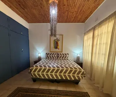 a bedroom with a bed and a chandelier at The Seed Pod Guesthouse in Haningfontein