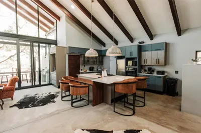 a kitchen with blue cabinets and a island with bar stools at Idyllic Kruger Breeze Marloth Park - 4 Bedroom in Marloth Park