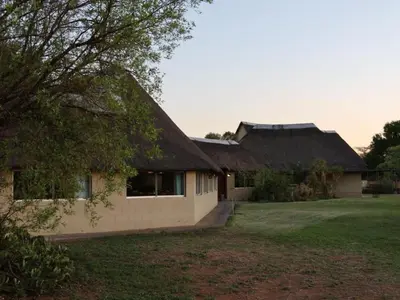a house with a thatched roof and a yard at Ngata Safari Lodge in Hammanskraal