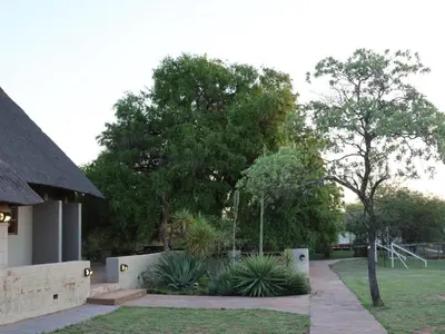 a garden with plants and trees in front of a building at Ngata Safari Lodge in Hammanskraal