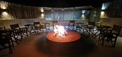 a fire pit in a restaurant with tables and chairs at Umlingo Lodge in Melkrivier
