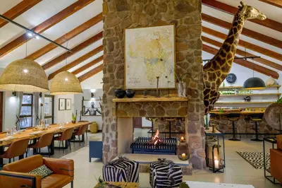 a restaurant with a fireplace with a giraffe on the wall at Umlingo Lodge in Melkrivier