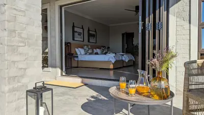 a bedroom with a bed and a table with drinks on it at Umlingo Lodge in Melkrivier