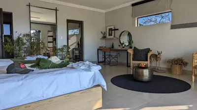 a bedroom with a bed and a room with a table at Umlingo Lodge in Melkrivier