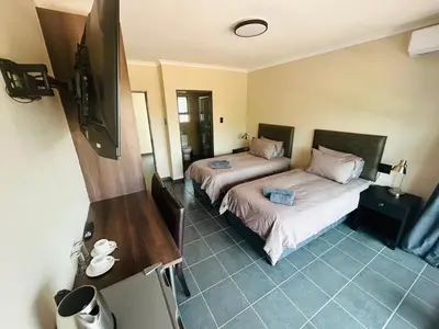 a room with two beds and a flat screen tv at Chill Out in Malelane