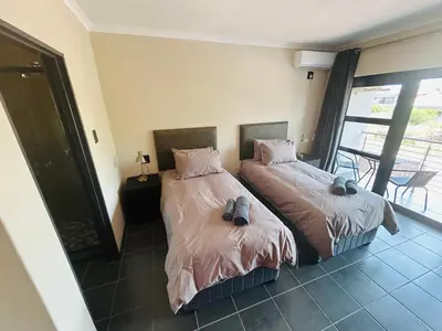 a bedroom with two beds and a balcony at Chill Out in Malelane