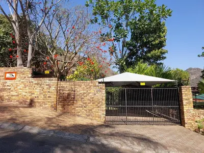 a brick fence with a gate with an umbrella at The Green Lizard Self-catering House in Nelspruit