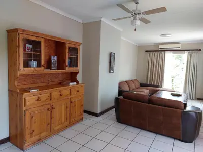 a living room with a couch and a large wooden cabinet at The Green Lizard Self-catering House in Nelspruit