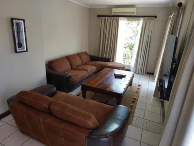 a living room with a couch and a table at The Green Lizard Self-catering House in Nelspruit