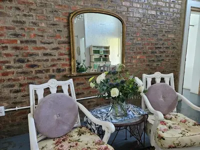 two chairs and a table in front of a mirror at Oudezwaanskraal Game Farm in Waaikraal