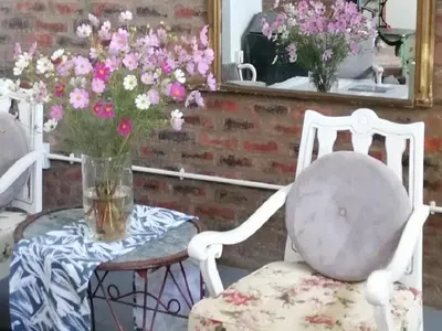 two white chairs and a table with a vase of flowers at Oudezwaanskraal Game Farm in Waaikraal