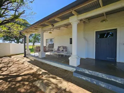 a white house with a porch with a patio at Oudezwaanskraal Game Farm in Waaikraal